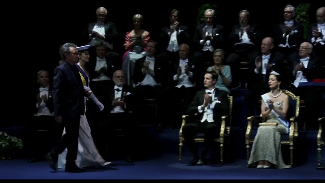 Video Reference: Music, Entertainment, Chair, Suit, Formal wear, Event, Performing arts, Fashion design, Audience, Crowd