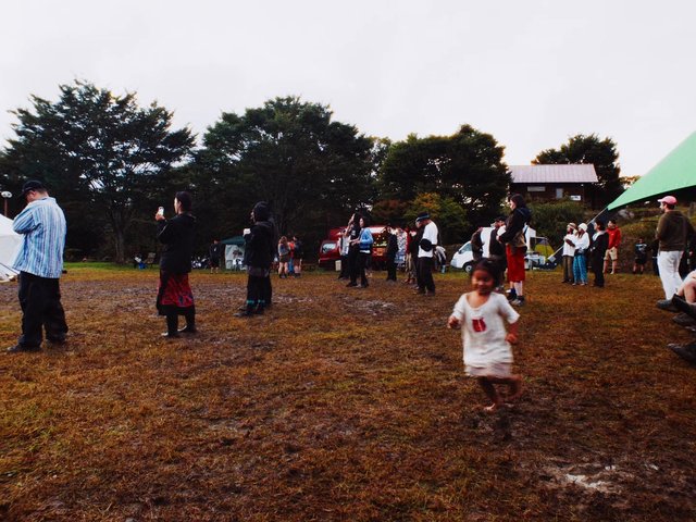 Video Reference: outdoor, gathering, crowd, field, mud, child, running, festival, tents, trees, daytime, people, grass, event
