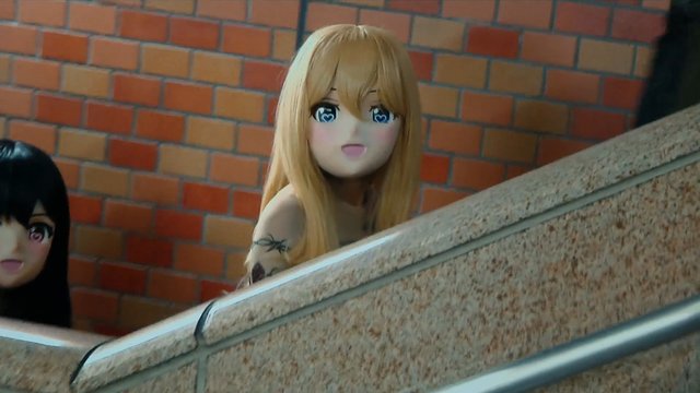 Video Reference: anime, animated, character, blonde hair, black hair, brick wall, staircase, railing, close-up, indoors, cartoon, manga, partially visible