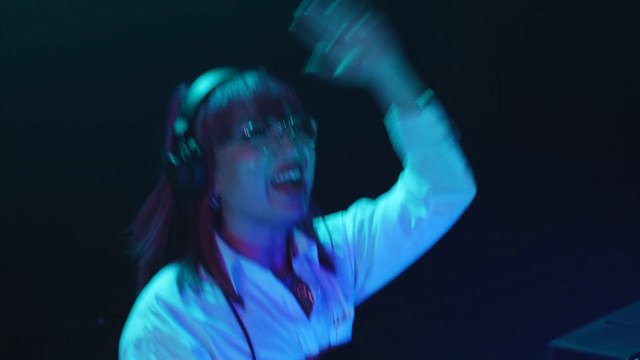 Video Reference: person, DJ, headphones, glasses, dance, music, club, stage lighting, performance, blurred motion, nightlife, entertainment, electronic music, crowdless, colorful lights