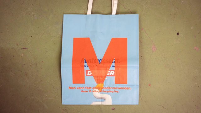 Video Reference: shopping bag, paper bag, blue, orange, recycling, German text, floor, handles, poster, advertising, flat lay, indoor, worn surface, retail, eco