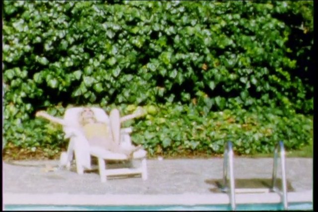 Video Reference: swimming pool, lounge chair, person, outdoors, foliage, ivy, poolside, relaxing, sunbathing, ladder, garden, summer
