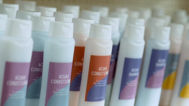 Video Reference: cosmetic bottles, hair care, conditioner, product shelf, packaging, close-up, rows, retail, bottles, plastic, colorful labels, shallow focus