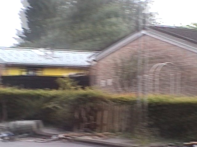 Video Reference: suburban, house, residential, street, hedge, trees, brick, roof, outdoor, neighborhood, blurred, empty, daytime