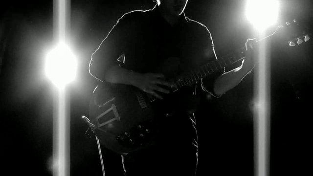 Video Reference: silhouette, guitar, electric guitar, musician, stage, concert, backlight, black and white, performance, live music, instrument, spotlight