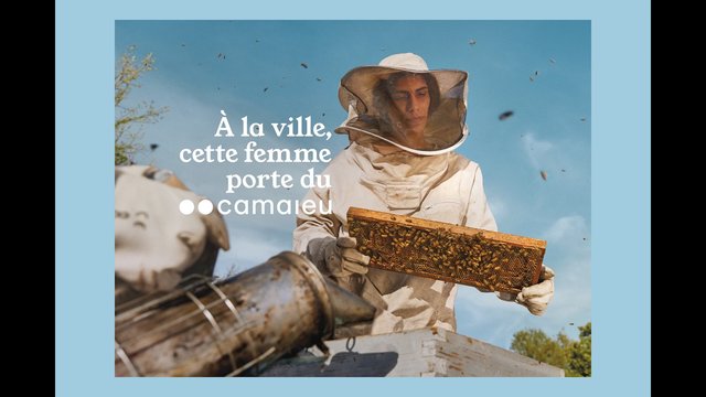 Video Reference: beekeeper, bees, honeycomb, protective suit, veil, outdoors, blue sky, apiary, hive, farming, nature, French text, advertisement, close-up, harvest