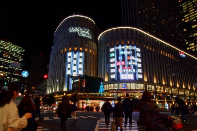 Video Reference: night, city, urban, shopping mall, architecture, pedestrians, street crossing, illuminated building, downtown, Japan, commercial district, traffic, nightlife, skyline, retail, cityscape
