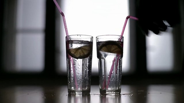 Video Reference: iced drink, glasses, lime, straws, beverage, refreshing, cocktail, mocktail, clear liquid, table reflection, backlit, window, close-up, drink presentation