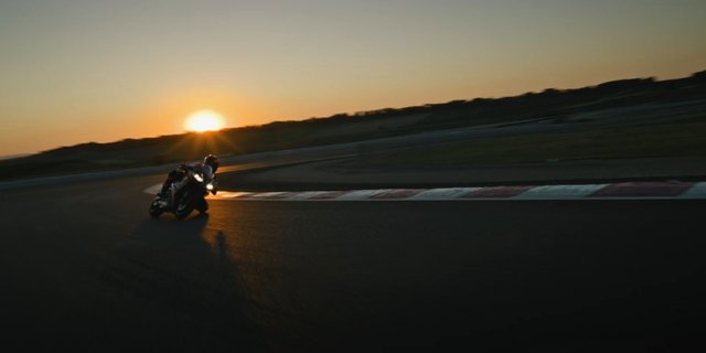 Video Reference: motorcycle, racing, racetrack, curve, turning, sunset, sports, speed, action, helmet, track, motion, outdoor, evening, leaning, silhouette
