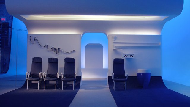 Video Reference: interior, futuristic, blue lighting, chairs, set design, architecture, minimalist, symmetry, corridor, stage, studio, modern, empty room, indoor, installation, geometric