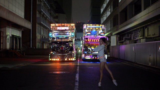Video Reference: night, street, urban, trucks, decorated truck, LED lights, colorful lights, vehicle, road, woman, outdoor, industrial, nighttime, city, transportation