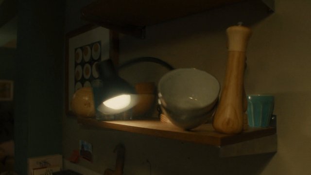 Video Reference: interior, shelf, home decor, lamp, wooden, bowl, cup, framed art, still life, dim light, household objects, indoor, shadow, warm tones