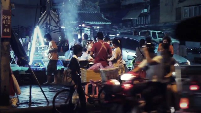 Video Reference: night market, street food, vendors, people, motorbike, bicycle, urban street, crowd, food stall, smoke, night scene, outdoor market, traffic, cars, street vendor