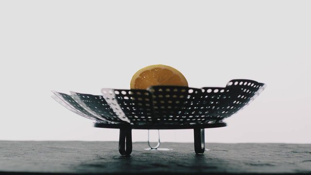 Video Reference: bowl, basket, metal, perforated, citrus, orange slice, still life, tabletop, minimal, close-up, indoor, object