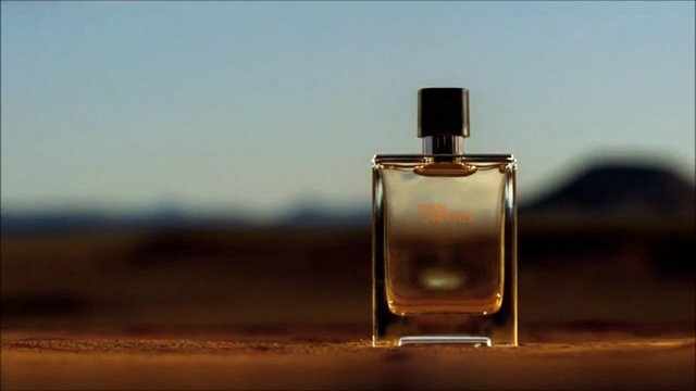 Video Reference: perfume, bottle, fragrance, glass, cosmetic, product shot, still life, outdoor, sunset, blurred background, luxury, advertising