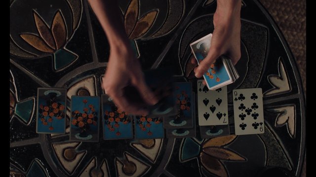 Video Reference: playing cards, card game, hands, deck, dealing, overhead, tabletop, patterned surface, tarot-style, game, close-up, strategy, shuffle, casino, flat lay