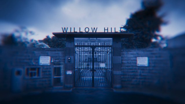 Video Reference: gate, entrance, building, sign, iron gate, school, campus, brick wall, blue tint, blurred, architecture, outdoor, fence, institution, front view