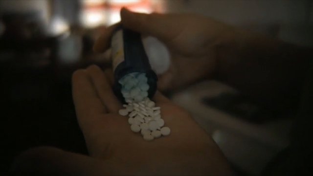 Video Reference: pills, medicine, bottle, hand, close-up, drug, tablets, medication, low light, spilling, dispensing, pharmacy, healthcare