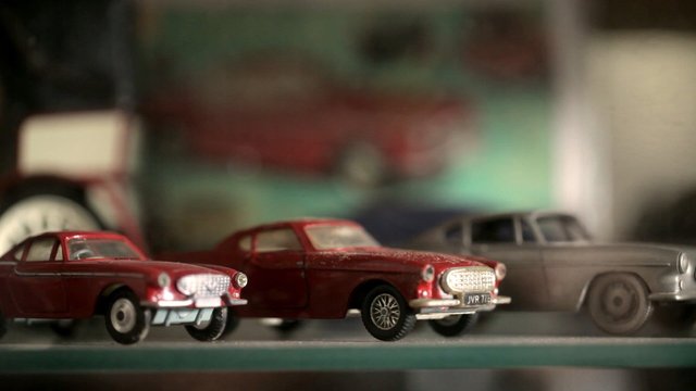 Video Reference: model cars, toy cars, miniature vehicles, red car, gray car, shelf, collection, close-up, shallow depth of field, indoor, vintage style, display