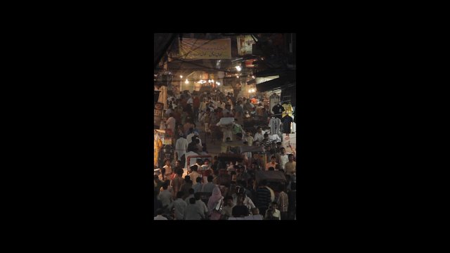 Video Reference: street market, bazaar, crowd, night, pedestrians, stalls, shopping, urban, busy, lights, outdoor, marketplace, traffic, people, narrow street, nightlife
