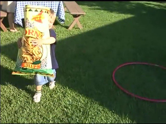 Video Reference: child, grass, outdoor, snack bag, picnic, yard, play, standing, summer, hoop, backyard, daylight