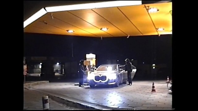 Video Reference: gas station, night, car, fuel pump, people, canopy, lights, forecourt, traffic cone, vehicle, outdoor, urban, nighttime, refueling