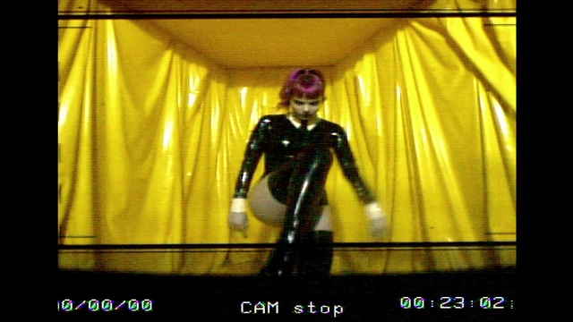 Video Reference: Yellow, Latex clothing, Entertainment, Curtain, Event, Latex, Performing arts, Display device, Fictional character, Electric blue