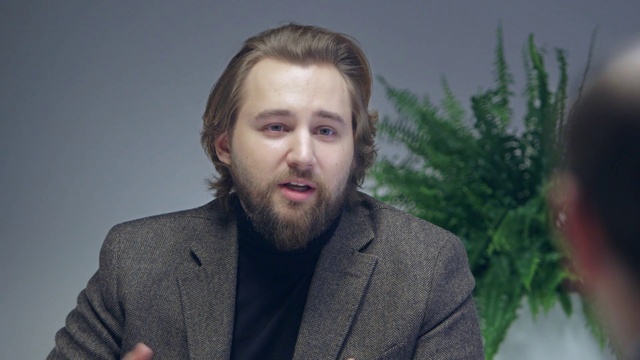 Video Reference: Forehead, Chin, Hairstyle, Eyebrow, Beard, Jaw, Coat, Gesture, Dress shirt, Plant