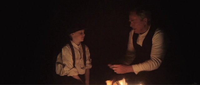 Video Reference: firelight, night, campfire, two people, adult, child, period clothing, conversation, dark scene, indoor darkness, historical, sitting