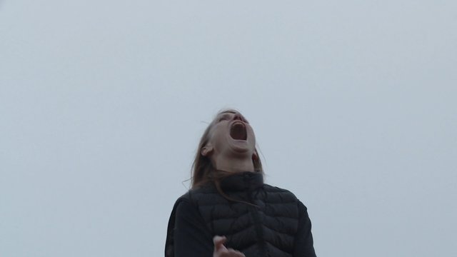 Video Reference: woman, outdoors, cloudy sky, low angle, shouting, yelling, portrait, jacket, overcast, sky, expression, human