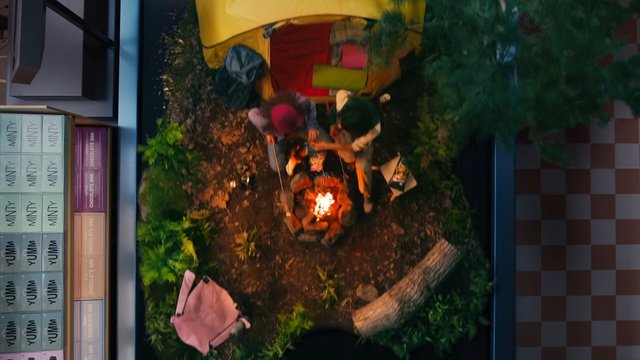 Video Reference: campfire, tent, campsite, forest, overhead view, people, backpacks, outdoors, night, trees, woods, supplies, store shelf, boxes, retail, top down