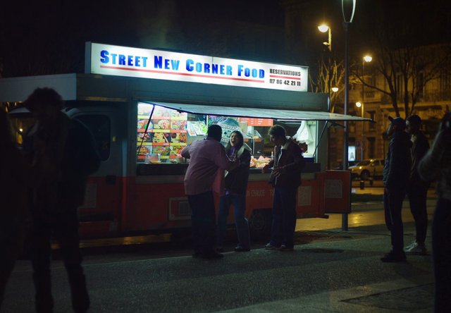Video Reference: night, street food, food truck, takeout, people, city street, outdoor, urban, illuminated, vendor, queue, social gathering, street scene, nightlife, fast food