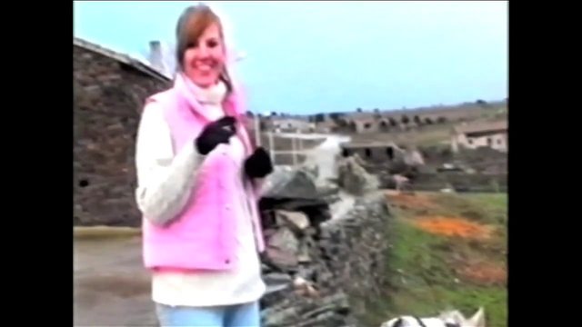 Video Reference: woman, outdoors, rural, stone wall, smiling, pink vest, gloves, landscape, vintage video, casual clothing