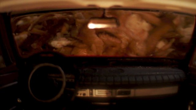Video Reference: car interior, windshield, dashboard, steering wheel, vehicle, blurry, dim light, night, close-up, inside car