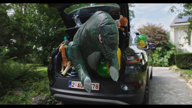 Video Reference: car, hatchback, open trunk, inflatable toys, stuffed animals, driveway, suburban, outdoor, playful, transport, packing, family