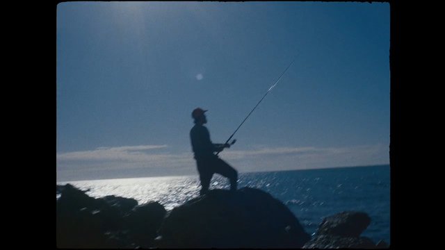 Video Reference: fishing, angler, silhouette, seaside, ocean, rocks, shoreline, outdoors, sunlight, horizon, nature, recreation