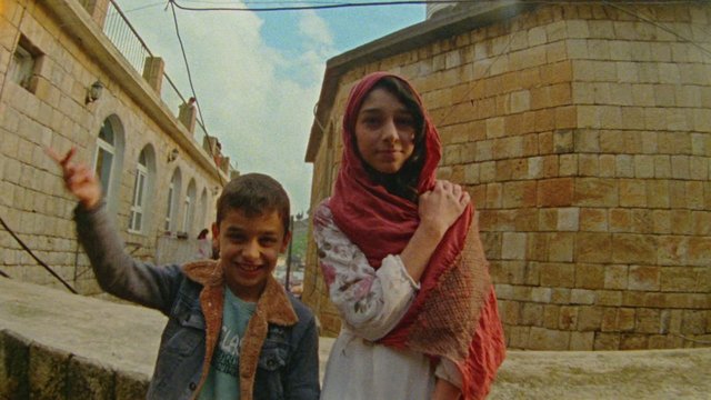 Video Reference: children, outdoors, stone buildings, street, waving, portrait, local scene, urban, headscarf, smiling, daylight, travel
