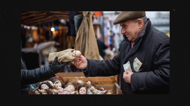 Video Reference: market, man, doll, toy, cash, vendor, outdoor, stall, shopping, handmade, antique, portrait, street, merchandise, curiosity, bokeh