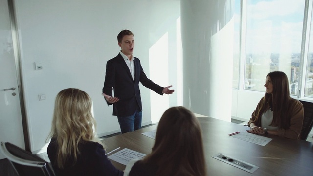 Video Reference: Table, Chair, Desk, Gesture, Suit, White-collar worker, Public speaking, Event, Presentation, Job
