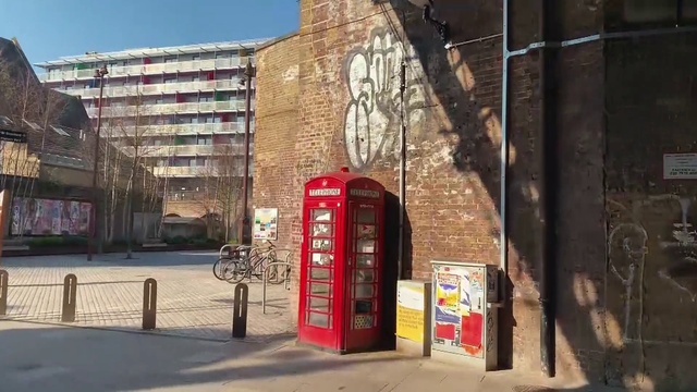 Video Reference: Building, Telephone booth, Bicycle, Wheel, Road surface, Sky, Neighbourhood, Wall, Tire, Facade