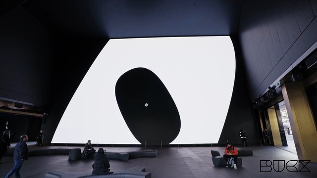 Video Reference: indoor, modern interior, lobby, gallery, abstract display, large screen, architecture, minimalist, people, seating, dark interior, public space, contemporary, wide angle