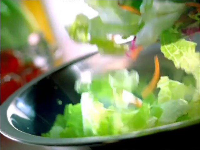 Video Reference: salad, lettuce, greens, bowl, food, cooking, fresh, vegetables, close-up, blurry, tossing, healthy, ingredient, kitchen