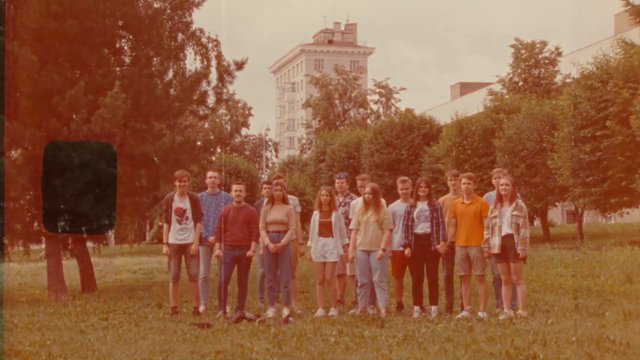Video Reference: group, people, outdoor, park, trees, grass, building, city, standing, young adults, portrait, wide shot, daylight, warm tint, urban