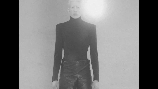 Video Reference: Shoulder, Neck, Flash photography, Jaw, Sleeve, Gesture, Grey, Style, Fashion design, Blazer