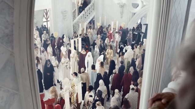 Video Reference: indoor, crowd, ceremony, robes, costumes, head coverings, ornate hall, stairs, columns, gathering, historic style, formal event, white interior, elevated view