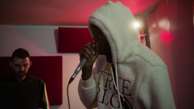 Video Reference: Microphone, Outerwear, Public address system, Musician, Audio equipment, Entertainment, Music, Performing arts, Music artist, T-shirt