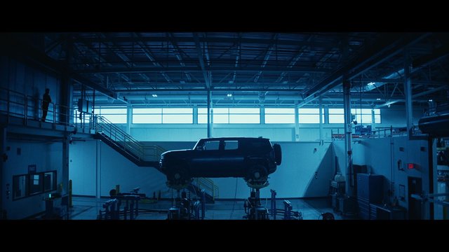 Video Reference: industrial, garage, laboratory, SUV, vehicle, testing rig, suspended, catwalk, stairs, warehouse, mechanical, blue lighting, indoor, factory, engineering, equipment