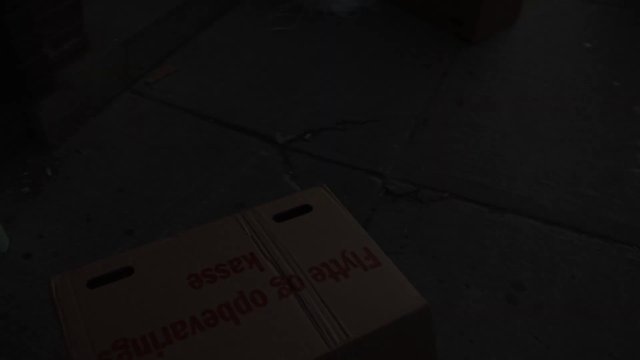 Video Reference: box, cardboard, floor, concrete, dark, low light, text, package, warehouse, still life