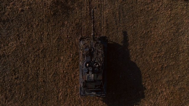 Video Reference: military vehicle, armored vehicle, tank, top down, aerial view, field, grassland, tire tracks, shadow, outdoor, camouflage, vehicle