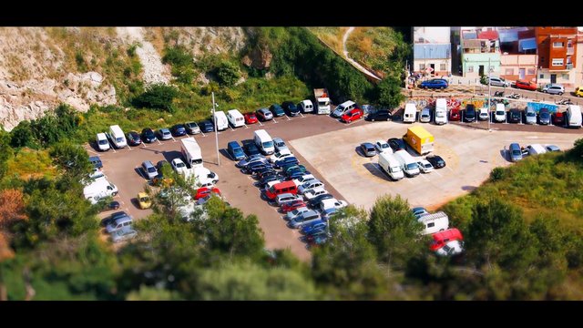 Video Reference: parking lot, cars, vans, aerial view, hillside, residential area, outdoor, daylight, urban, vehicles, road, trees, landscape, crowded, travel